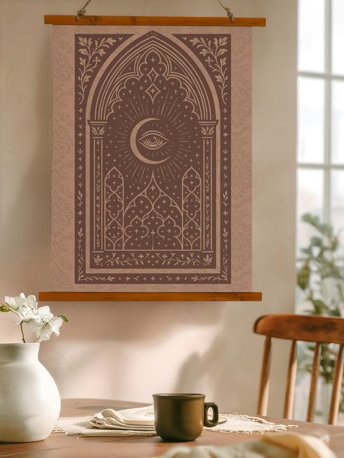 A large, luxurious tapestry in muted mauve and brown, featuring a Gothic arch design. In the center, a crescent moon holds an All-Seeing Eye that radiates light. The design is filled with intricate patterns like quatrefoils and stars, creating a mystical, esoteric feel. The fabric has a subtle damask texture and is hung from wooden dowels. This piece is suitable as spiritual wall art, a witchy altar cloth, or dark academia decor, blending celestial and gothic aesthetics.